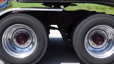 Driving beside commercial tractor trailer. Detail of burgundy wheels and trailer hitch. Highway driving in Ontario, Canada.