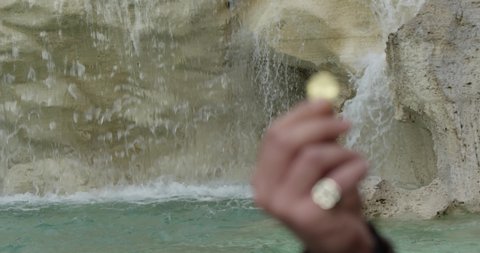 Focus priority: Hand of a tourist who throws a coin in the Trevi Fountain in Rome, Italy. Slow motion 50fps 4k