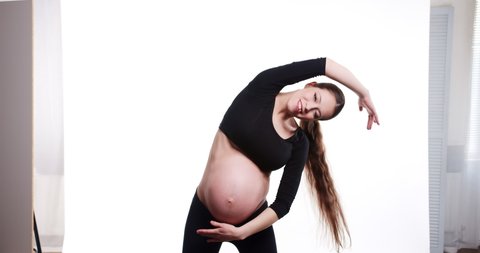 Happy smiling young pregnant woman doing yoga exercises. Beautiful belly mother making fitness workout isolated on white background. Prenatal yoga exercises.