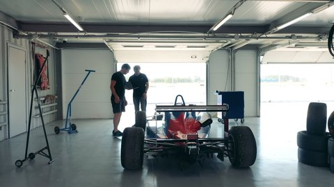 Servicemen are checking a racing car in a workshop