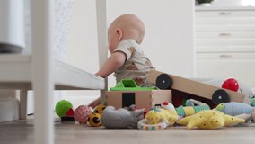 Baby sitting on the floor playing with toys, cute little baby boy having fun exploring new world, 7 month old caucasian toddler learns to crawl and sit. High quality 4k footage
