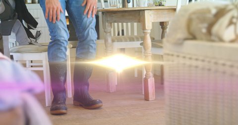 Animation of light over low section of man in kitchen wearing wellington boots. domestic life and positivity concept digitally generated animation.