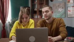 Young Couple staying at home using laptop computer for attending online course together, man and woman talking and learning new skills about healthy food or language, remote video lesson or work