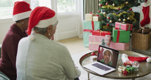 Diverse senior female friends using laptop for christmas video call with happy boy on screen. christmas, festivity and communication technology.