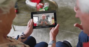 Senior caucasian couple using tablet for christmas video call with happy men on screen. christmas, festivity and communication technology.