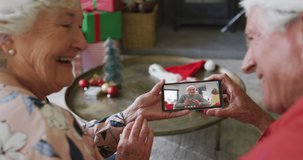 Senior caucasian couple using smartphone for christmas video call with happy man on screen. christmas, festivity and communication technology.