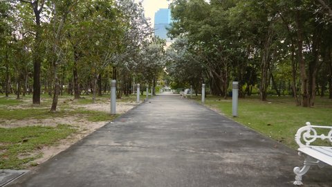 First person view walking in empty public park. Green trees in outdoors recreational place in modern city, no people. Urban place to rest among nature. Healthy lifestyle. Nobody around. Slow motion.