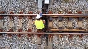 Arial view showing engineer under inspection and checking construction process railway switch and checking work on railroad station by taplet.Engineer wearing safety uniform and safety helmet.