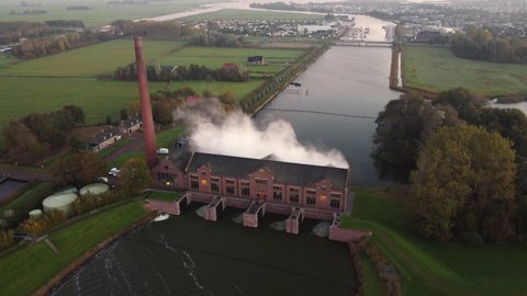 Steam rising up from the old Woudagemaal Steam Pumping Station in Lemmer, Friesland, during sunrise. Drone view from above.