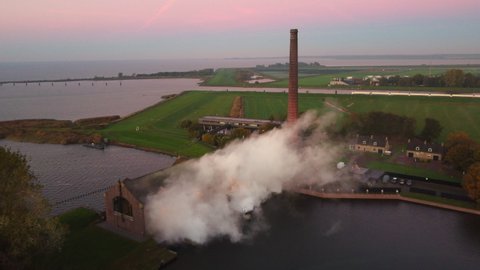 Steam rising up from the old Woudagemaal Steam Pumping Station in Lemmer, Friesland, during sunrise. Drone view from above.