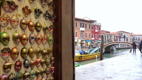 Europe, Italy , Murano November 2021 - 
souvenirs in the shape of Carnival masks typical of Venice and Murano in a shop with a window on the canals of the city of love