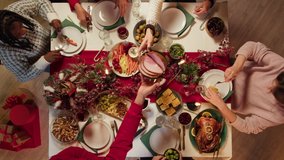Friends celebrating new year, sitting at dining table top view. International young people eating delicious dishes, putting food on plates. Diverse students during christmas party at home.  - Powered by Shutterstock - Get 15% off with code: PIKWIZARD15