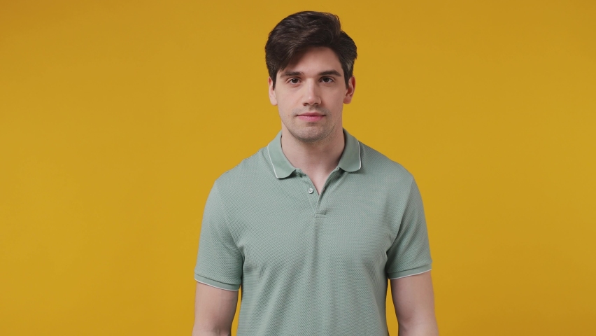 Fun confused awkward confused preoccupied shy shamed young man 20s years old wear blue t-shirt look camera spreading hands say oops ouch oh omg i am so sorry isolated on plain yellow background studio Royalty-Free Stock Footage #1082671726