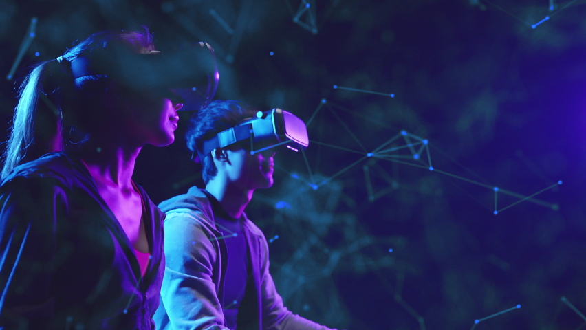 Metaverse VR virtual reality game playing, man and woman play metaverse virtual digital technology game control with VR goggle | Shutterstock HD Video #1082675401