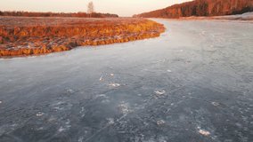Orange coast and lake covered with ice, aerial view. In winter, at sunset, in the evening. Screensaver, footage, nature for intro, background, titles. UHD 4K.