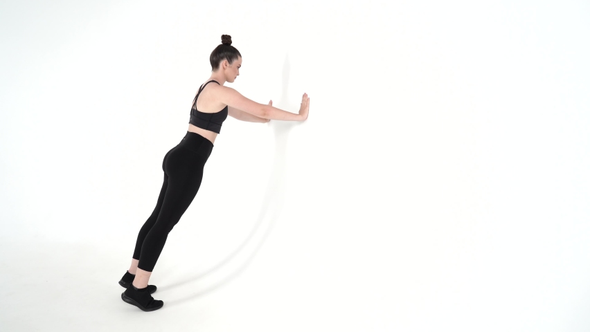 Certified female fitness trainer executing wall push ups on a white background . Upper body strength exercises for beginners-intermediate  level  