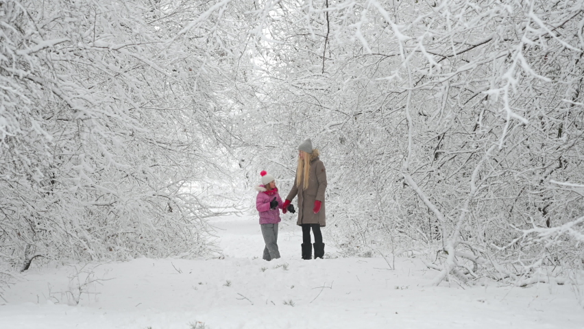 Happy mom plays with her daughter in a beautiful winter park. Family walks outdoors in cold winter. Royalty-Free Stock Footage #1082684686