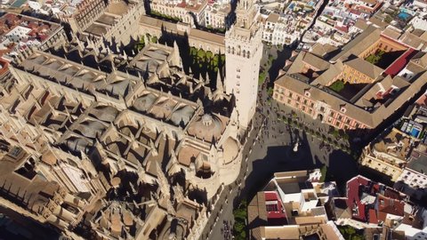 Aerial drone footage of the gothic cathedral in Seville old town with its famous Giralda bell tower, an ancient minaret, in Andalusia, Spain. Shot with a tilt up motion. 
