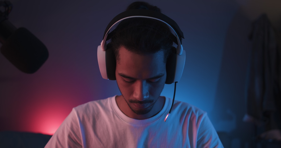 Young confident Asian man start playing online computer video game, colorful lighting broadcast streaming live at home. Gamer lifestyle, E-Sport online gaming technology concept Royalty-Free Stock Footage #1082687326