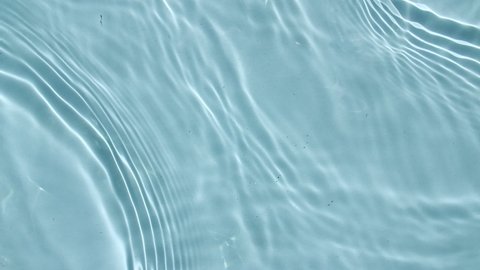 Water surface texture top view. Water splash blue colored. Pure blue water with reflections sunlight in slow motion. Sun and shadows. Motion clean swimming pool ripples and wave. 4k