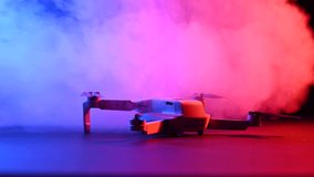 Drone in clouds of colored pink-blue smoke on a black background.