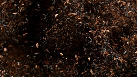 Super slow motion of dry tea leaves flying in the air on a black background, 1000 fps.
