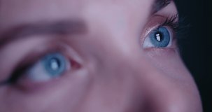 Extreme close up macro of beautiful woman blue eyes addicted by social network, looks into a smartphone screen with fast flickering social network feed, posts. Blinking screen reflection in eyes