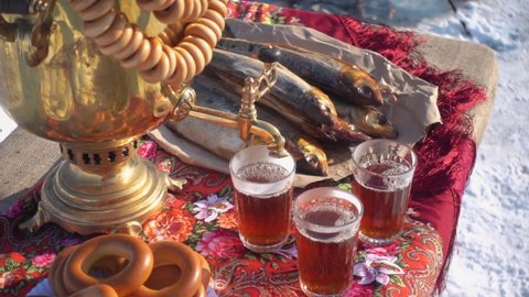 Russian still life on lake Baikal traditional treat cuisine. Samovar, hot tea, omul local fish, bagels on table, traditional painted scarf. Tourist lunch serving. Authentic culture style. Siberia tour
