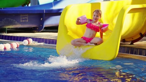 time-lapse. a little girl rolls down a slide in a water park. entertainment for children in the pool. extreme and fun rides. 