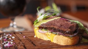 Stock food video of sandwich with beef meat served on rustic wooden plate for lunch in restaurant