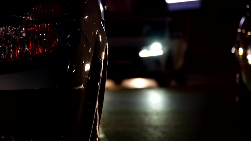silhouette of a woman walking at night between car lights