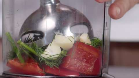 cook lowers submersible blender and grinds red pepper, garlic, dill close-up slow motion