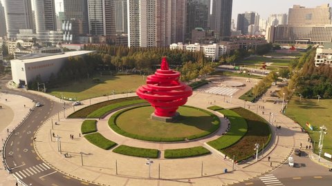November 21, 2021 - Qingdao, China: May Fourth Wind sculpture in May Fourth Square. Skyscrapers and sun in the background