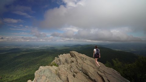 Charlottesville, VA, USA - 10032021: Young woman hikes up a rock face to enjoy the success of a climb and the view of Virginia.