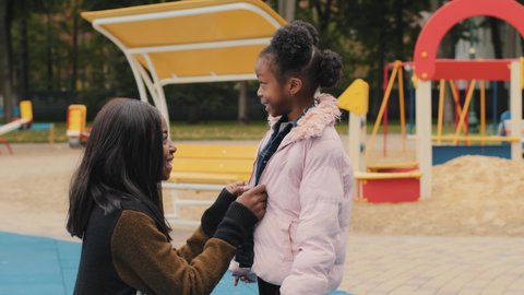 Side view mom laugh with daughter in playground cute little girl tell funny story mother smiling listening to kid child emotionally talking outdoors family happily spend time after school caring mommy