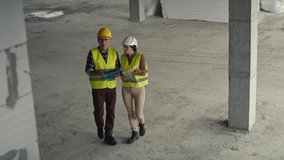 High angle view  video of male and female caucasian engineers discussing and pointing on the construction site. Shot with RED helium camera in 8K 