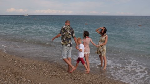 A happy family with children, daughter and son, walking on the beach by the sea in summer. Family, happiness, travel concept.
