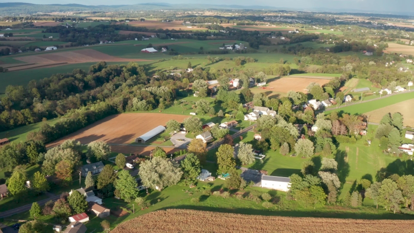 Summer aerial of rural town, village in USA among farmland. Beautiful golden hour light and shadows.