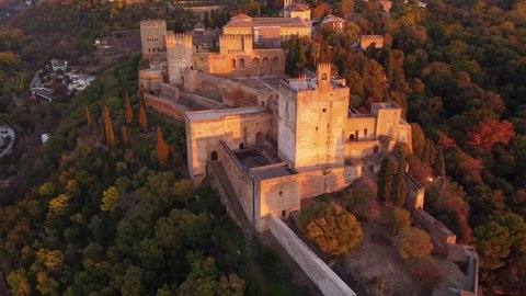 Dramatic aerial drone footage of the famous Alhambra palace and fortress in Granada, Andalusia, in Spain at sunset. Shot with a backward tilt up motion. 