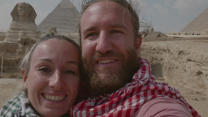Young couple travelling take a selfie in front of the Great Pyramids of Giza. Couple take selfies in Cairo, Egypt, with Pyramids and Sphinx 