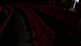 This panning video shows an empty movie theater lined with empty red seats.
