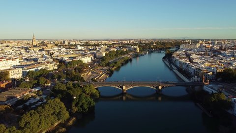 Aerial drone footage of the Seville city along the Guadalquivir canal with various landmark such as the cathedral, the Torre del Oro and the Bull area in Andalusia, Spain