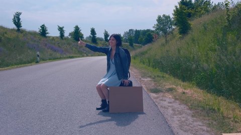 The concept of travel and hitchhiking. A young girl who hitchhikes and stops the car on the road.
