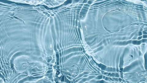 Water surface texture top view. Water waves blue colored. Sun and shadows. Pure blue water with reflections sunlight in slow motion. Motion clean swimming pool ripples and wave. 4k