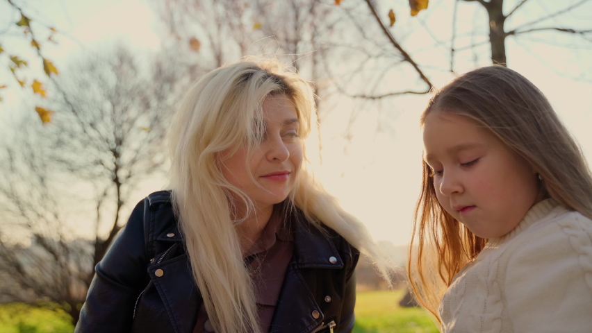 Mother and daughter have picnic at autumn park outdoors. Two females smile and laugh spending good time together. Woman hug girl child. Motherhood and childhood concept