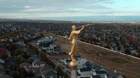 AERIAL ORBIT AROUND ANGEL MORONI ATOP OF LDS MORMON OQUIRRH MOUNTAIN UTAH TEMPLE WITH BEAUTIFUL VIEW OF SOUTH JORDAN CITY AND THE CLOUDY MOUNTAINS