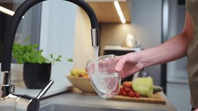 Woman pouring water from faucet into glass at the kitchen - Powered by Shutterstock - Get 15% off with code: PIKWIZARD15