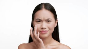 Young Japanese Lady Touching Skin Under Eyes Worried About First Wrinkles And Black Circles Under Eyes Looking At Camera Standing Over White Studio Background. Facial Skincare, Skin Problems