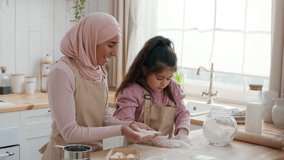 Muslim Mommy And Little Daughter Having Fun With Flour Clapping Hands And Laughing While Baking Cookies Together In Kitchen At Home. Arabic Mother And Her Kid Bonding Enjoying Cooking On Weekend