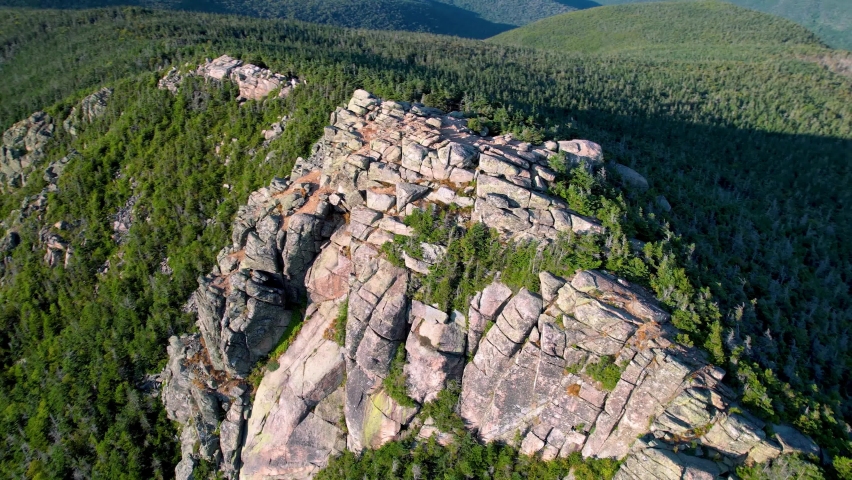 Aerial shot orbiting an impressive rock formation, New Hampshire USA. Top cinematic aerial shot. Beautiful mountainous desert landscape. Panoramic view of the sheer cliff. 